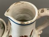 a small pitcher and a small cup sitting on a table