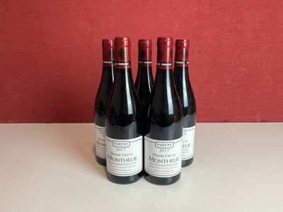 trois bouteilles de vin rouge sont posées sur une table devant un mur rouge