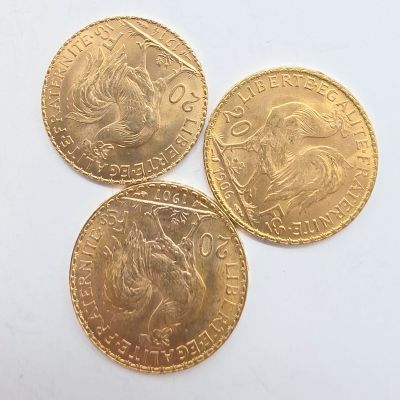 trois pièces d'or superposées sur une surface blanche