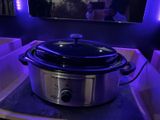 a crock pot sitting on a counter with a tv in the background