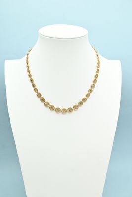 a gold chain necklace with a coin design on a mannequin