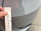 a person holding a measuring tape to measure the front of a car