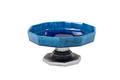 un petit bol bleu posé sur un socle, sur fond blanc