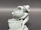 une figurine représentant un garçon avec un panier sur la tête