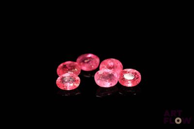 un gros plan sur une paire de diamants roses posés sur une surface noire