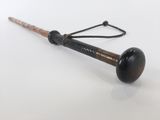 une vieille batte de baseball avec un manche en bois, posée sur une surface blanche