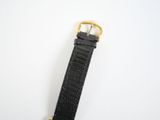 black leather watch strap with gold buckle on a white surface