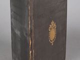 an old black book with a gold emblem on the cover