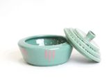 green ceramic bowl with lid and lid open on a white surface