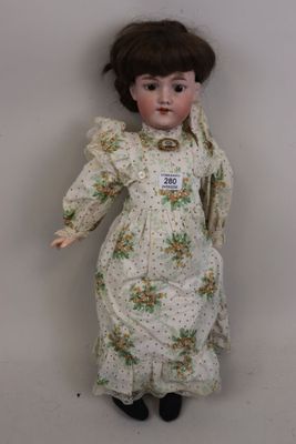 une vieille poupée en porcelaine aux cheveux bruns, vêtue d'une robe et chaussée de souliers