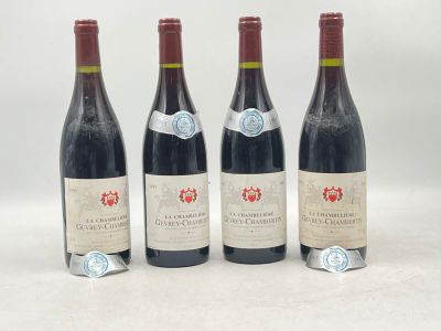 quatre bouteilles de vin sont alignées sur une surface blanche