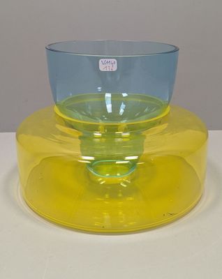 un bol en verre jaune et bleu posé sur une assiette jaune
