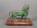 bronze statue of a lion on a marble base on a gray background