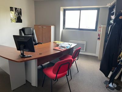 un bureau avec un écran d'ordinateur et des chaises rouges dans une pièce