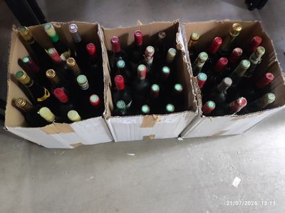plusieurs bouteilles de vin posées dans une caisse posée par terre
