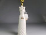 un vase blanc surmonté d'une couronne dorée