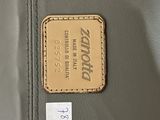 someone is holding a gray bag with a brown tag on it