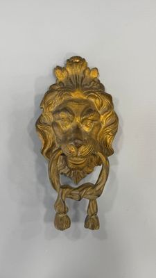 poignée de porte en forme de tête de lion en laiton sur un mur blanc