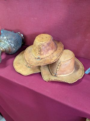 trois chapeaux posés sur une table rouge à côté d'un vase bleu