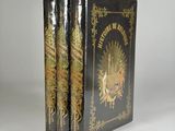 two black books with gold designs on them sitting on a white surface