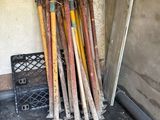a pile of baseball bats and a shovel in a garage