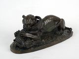 statue en bronze représentant un chien allongé sur une bûche, un poisson dans la gueule