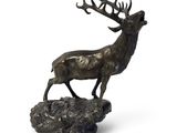 sculpture en bronze représentant un cerf debout sur un rocher, avec ses bois