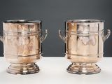 deux vases en argent posés sur une table, sur fond noir