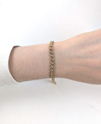 Quelqu'un porte un bracelet en or orné de pierres vertes.