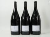 three bottles of red wine sit on a white surface