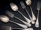 six silver spoons and a fork on a black surface