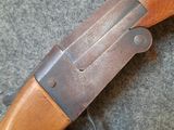 a close up of a rifle with a wooden handle on a carpet