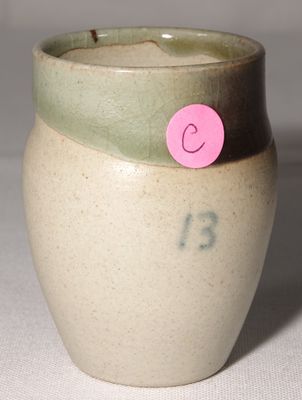 un petit vase sur lequel est collé un autocollant rose