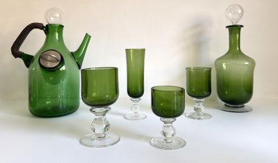 Des bouteilles et des verres sont alignés sur une table, à côté d'un pichet