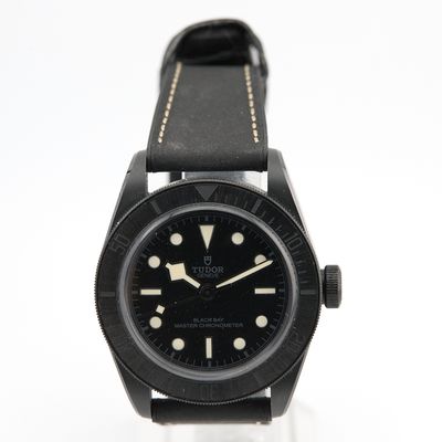 une photo d'une montre noire montée sur un bracelet en cuir noir