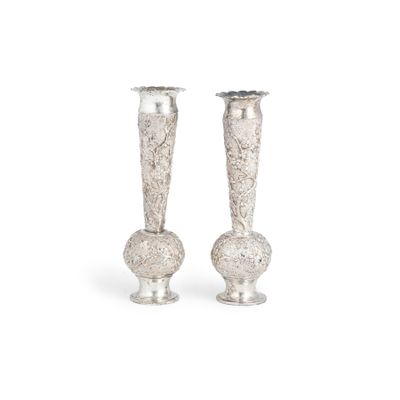 une paire de vases en argent empilés l'un sur l'autre sur une surface blanche