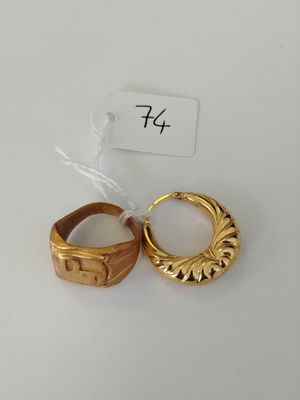 two gold rings on a white surface with a price tag