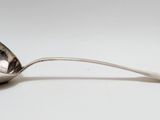 une cuillère en argent avec un manche de cuillère sur une surface blanche