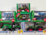 three green tractors in boxes on a white surface