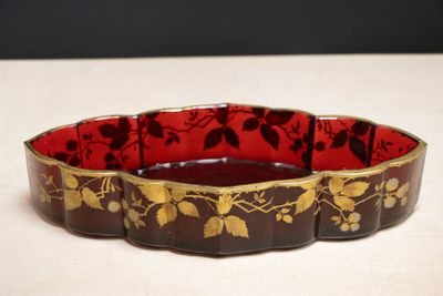 un bol rouge et doré posé sur une table blanche