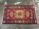 a red and blue rug sitting on top of a cement floor
