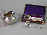 a silver pitcher next to a silver spoon and a purple box