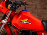 a red honda motorcycle parked in front of a brick wall