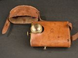 an old leather case with a brass button on a black surface
