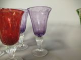 purple and red glass goblets sitting next to each other on a table