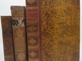 three old books sitting on top of each other on a white surface