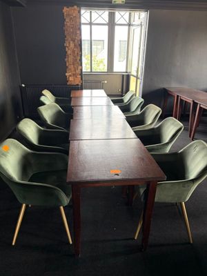 de nombreuses chaises vertes disposées autour d'une longue table dans une pièce