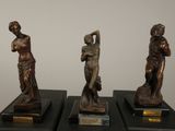 three bronze statues of a woman and a man on a black pedestal