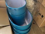 trois seaux en plastique bleus empilés les uns sur les autres sur un plancher en bois