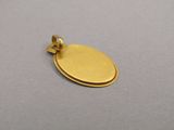 a close up of a gold oval pendant on a gray surface